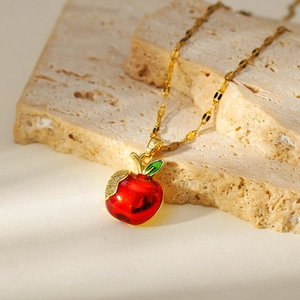 Gold apple necklace with red enamel pendant and zircon leaf on natural stone blocks