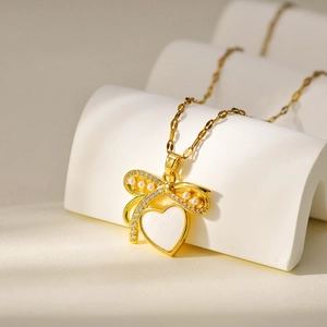 Elegante gouden hartketting met strik, wit parelmoer en microparel accenten