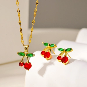 Detailed view of cherry pendant necklace and earrings with red and green gemstones