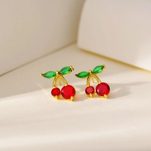 Macro shot of gold-plated cherry earrings with red round and green marquise crystals
