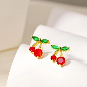 18K gold plated cherry earrings with red and green crystals on a white pedestal