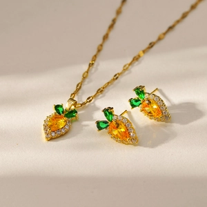 Detail shot of carrot-shaped gold jewelry set with orange stones and white zircons