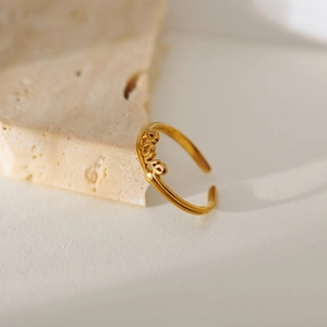 Minimalist gold-plated stainless steel Love ring displayed on natural stone