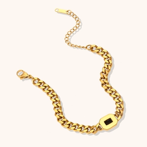 Detail view of gold Cuban link bracelet with black square gemstone and lobster clasp