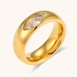 Gros plan d'une bague dorée polie ornée d'un zircon marquise sur fond beige épuré