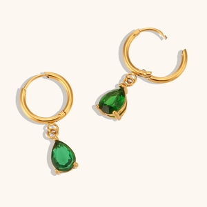 Gros plan de boucles d'oreilles créoles dorées avec gouttes de zircon vert taille poire