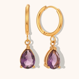 Gros plan de boucles d'oreilles créoles dorées avec pendentifs en zircon violet