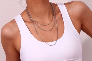 Gros plan d'un collier triple rangée argenté minimaliste sur un mannequin