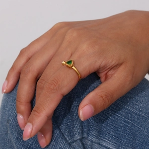 Primo piano di un anello in oro 18K con zircone verde a cuore sulla mano di un modello