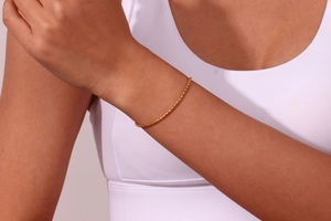 Gros plan d'un bracelet à maillons carrés plaqué or minimaliste porté sur un poignet féminin