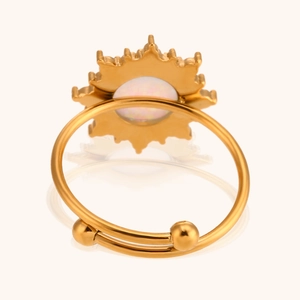 Detalle de anillo ajustable dorado con opalo blanco y diseño de sol resplandeciente