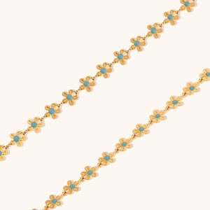 Close-up of gold-plated bracelet with blue enamel flower beads and fine chain links