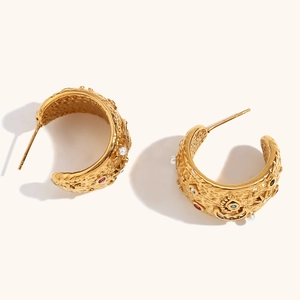 Detail of vintage gold C-shape earrings with colorful rhinestones and white pearls