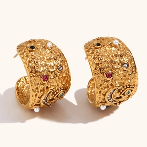 Detail of gold-plated hoop earrings with hammered texture, colored zircons, and pearl accents