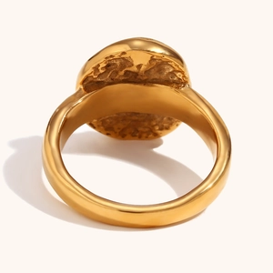 Detailed macro view of gold-plated textured signet ring featuring a unique hammered pattern