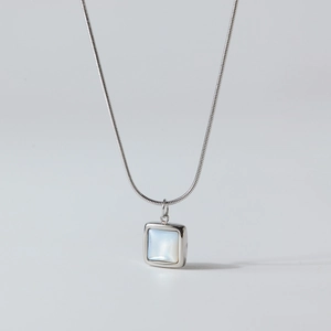 Macro detail of square mother-of-pearl pendant on a silver snake chain necklace