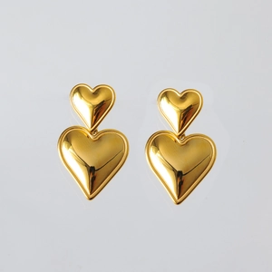 Dettaglio macro degli orecchini a doppio cuore in acciaio inossidabile placcato oro 18K lucido