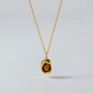 Detail of gold necklace with organic pendant and brown tiger eye stone centerpiece