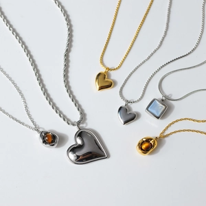 Assorted gold and silver plated heart necklaces with gemstone pendants on white background