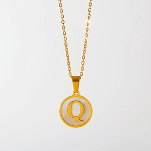 Detail van gouden ketting met ronde hanger, letter Q en inleg van wit parelmoer