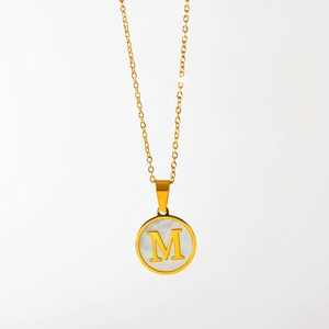 Detail van de gouden hanger met letter M en witte parelmoer inleg aan een O-ketting