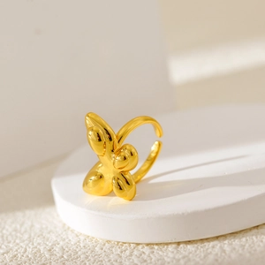 Minimalistischer goldener Schmetterlingsring mit polierter Oberfläche auf weißem Sockel