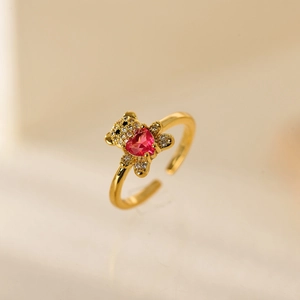 Dettaglio dell'anello dorato con orsetto e pietra di zircone rosso a forma di cuore