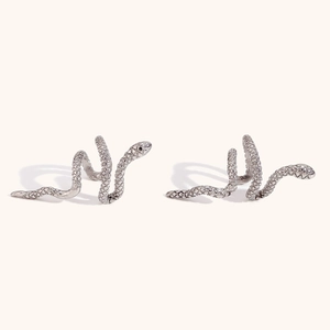 Macro shot of silver snake-shaped ear cuffs with realistic scale texture and metallic finish