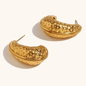 Detailopname van gouden oorbellen met gehamerde textuur en een luxe 18K vergulde afwerking