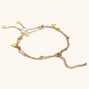 Detail of double-layer gold anklet with heart pendants and white shell inlay