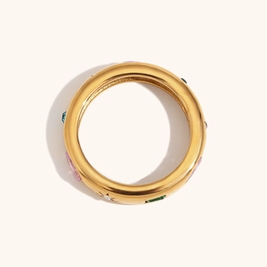 Détail d'une bague dorée ornée de zircons colorés avec une finition polie miroir