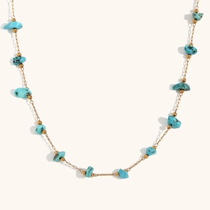 Detalle de fragmentos de turquesa natural y cuentas doradas en un collar delicado