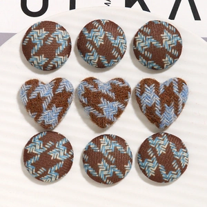 Brown and blue houndstooth fabric buttons in round and heart shapes on a plate