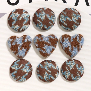 Detailed view of houndstooth fabric buttons in round and heart shapes for DIY sewing