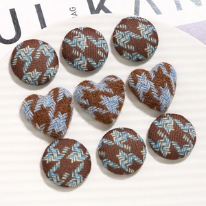 Detailed view of round and heart-shaped brown houndstooth fabric buttons for DIY jewelry