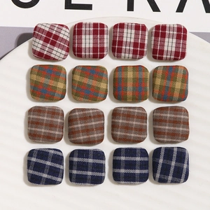 Macro view of 16 square fabric buttons in four classic plaid and check patterns for DIY crafts