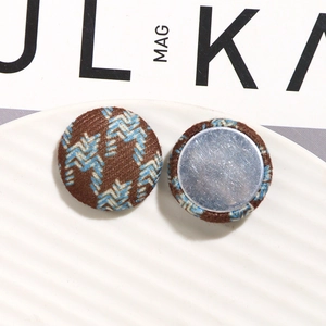 Detailed close-up of brown and blue houndstooth fabric buttons with silver metal base