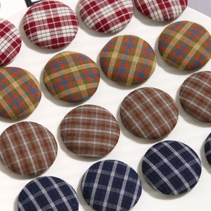 Plaid fabric covered round buttons for DIY accessories shown in a white ceramic dish