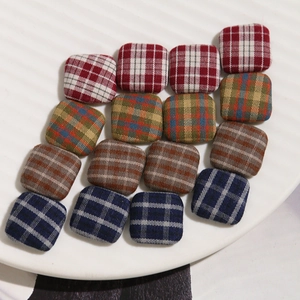 Macro detail of square fabric-covered buttons in vintage plaid for DIY jewelry making