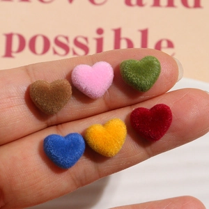 Detailopname van mini geflokte hartbedeltjes in diverse kleuren voor DIY sieraden