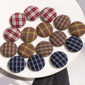 Detail shot of assorted retro plaid fabric covered buttons in a white ceramic dish