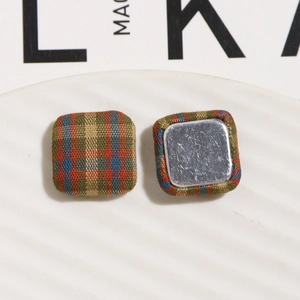 Detailed view of square plaid fabric buttons with green and orange tartan pattern