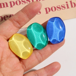 Close-up of colorful cat-eye resin cabochons in hand for earring and DIY jewelry making