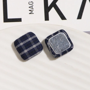 Macro detail of square blue plaid fabric buttons with smooth metal backing for DIY crafts