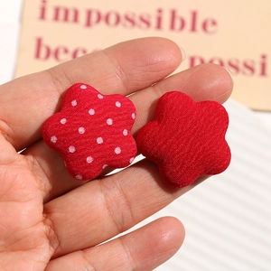Handheld view of red fabric flower buttons with polka dots for DIY jewelry making