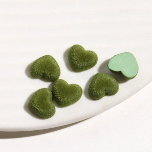Detailopname van groene hartvormige geflockte bedeltjes voor DIY sieraden op bord