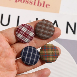 Close-up of assorted vintage fabric plaid buttons held between fingers for DIY accessories