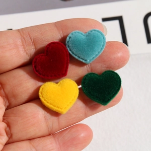 Close-up of four-color velvet heart patches with fine stitching for DIY hair accessories