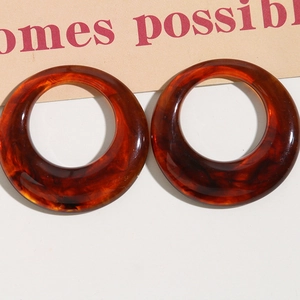 Vista macro de pendientes de aro de resina marrón rojizo con textura de carey retro