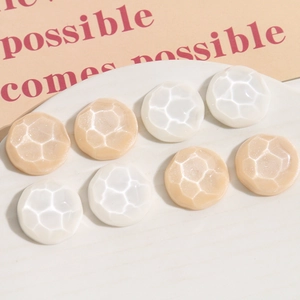 Detail of round resin shoe buckles with hexagonal honeycomb texture in white and champagne